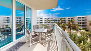 Un balcon avec une table et des chaises, donnant sur une piscine et un bâtiment faisant partie d’un complexe hôtelier.