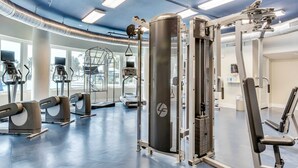 Une salle de sport équipée de divers appareils d’exercice, notamment des tapis de course, des appareils elliptiques et des machines de musculation.