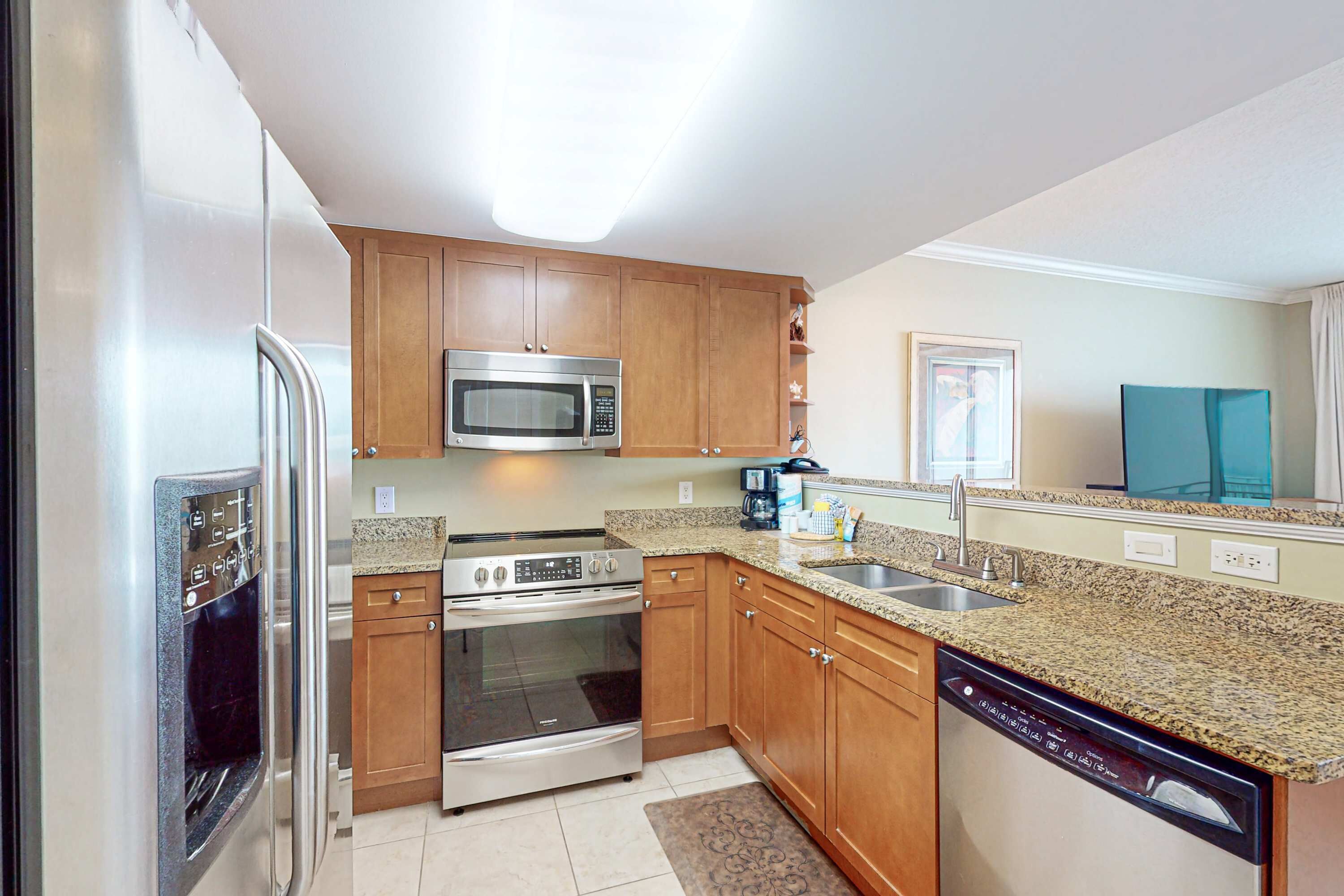 A modern kitchen with stainless steel appliances, wooden cabinets, granite countertops, and a dishwasher.