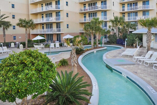 A hotel pool area with lounge chairs and palm trees. - 2nd Floor Spacious Condo On Okaloosa Island Waterfall, Lazy River (Fort Walton Beach)