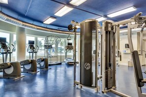 Ein Fitnessstudio mit Laufbändern, Kraftgeräten und einer Hantelbank.