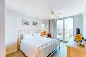 Ein Hotelzimmer mit einem Bett, einem Schreibtisch mit Lampe, einem Sessel, einem Fernseher und einem Balkon mit Blick.