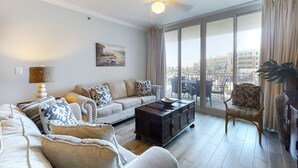 Een moderne woonkamer met een bank, fauteuils, een salontafel en een plafondventilator.