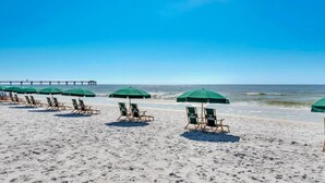 Een strand met rijen groene parasols en houten strandstoelen.