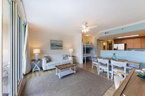 Un salon spacieux avec un canapé blanc, une table basse et un coin repas comprenant des chaises et une table, le tout dans des tons blancs.