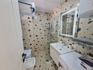 A bathroom with a shower, two sinks, a mirror, and a towel rack. - Sea view luxury duplex (Durrës)