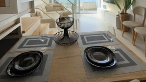A modern dining area with a wooden table, two chairs, and a black bowl centerpiece.