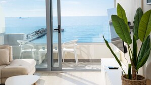A modern living room with a large sliding glass door leading to a balcony with a sea view.