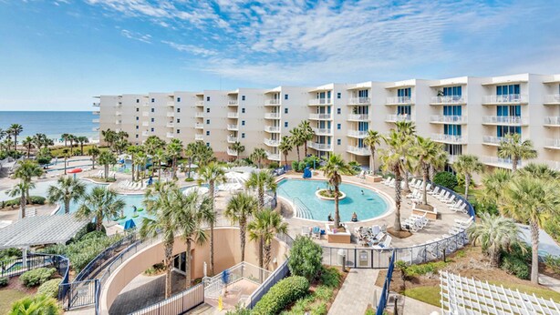A resort with multiple floors, a central pool, and palm trees. - Bright, beachy condo At Waterscape w children's playground, 2 hot tubs (Fort Walton Beach)