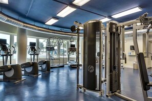 Ein Fitnessstudio mit Laufbändern, Kraftgeräten und einer Hantelbank.