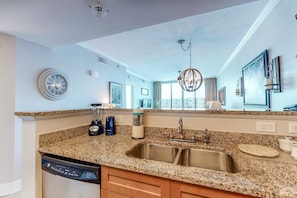 A modern kitchen with granite countertops, a double sink, and a dishwasher. - Elegant, Spacious Condo At Waterscape Children's Playground, 2 Hot Tubs (Fort Walton Beach)