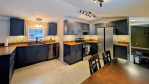 Una cocina moderna con armarios oscuros, electrodomésticos de acero inoxidable y una mesa de comedor de madera.