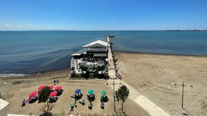 A beachside building with a covered patio area, a sandy beach, and a pier extending into the water. - Sea view -Blue Wave Two (Durrës)