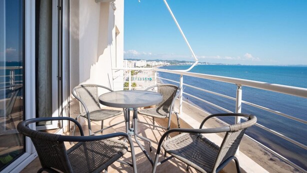 A balcony with wicker chairs and a table, overlooking a beach and the sea. - Sea view -Blue Wave Two (Durrës)