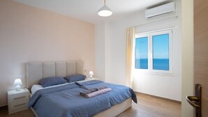 A bedroom with a bed, nightstands, a window with a view, and an air conditioning unit. - Sea view -Blue Wave Two (Durrës)