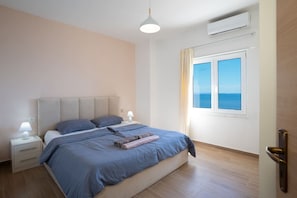 A bedroom with a bed, nightstands, a window with a view, and an air conditioning unit. - Sea view -Blue Wave Two (Durrës)