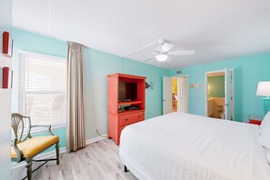 Une chambre à coucher avec un lit, un bureau, une chaise et une fenêtre avec des rideaux.