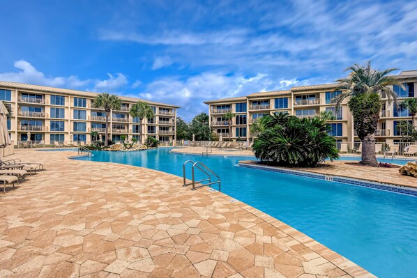 Un hotel con piscina, varios balcones y palmeras.