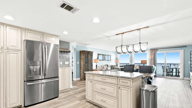A modern kitchen with stainless steel appliances, a large island, and a view to the outside. - Oceanfront condo with pool, ocean view, washer&dryer, & high-speed WiFi (Fort Walton Beach)