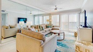 A modern living room with a sofa, coffee table, and TV. - Platinum penthouse with balcony views, pool, tennis court & beach access (Fort Walton Beach)