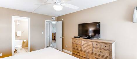A bedroom with a bed, a dresser, a television, and a ceiling fan.