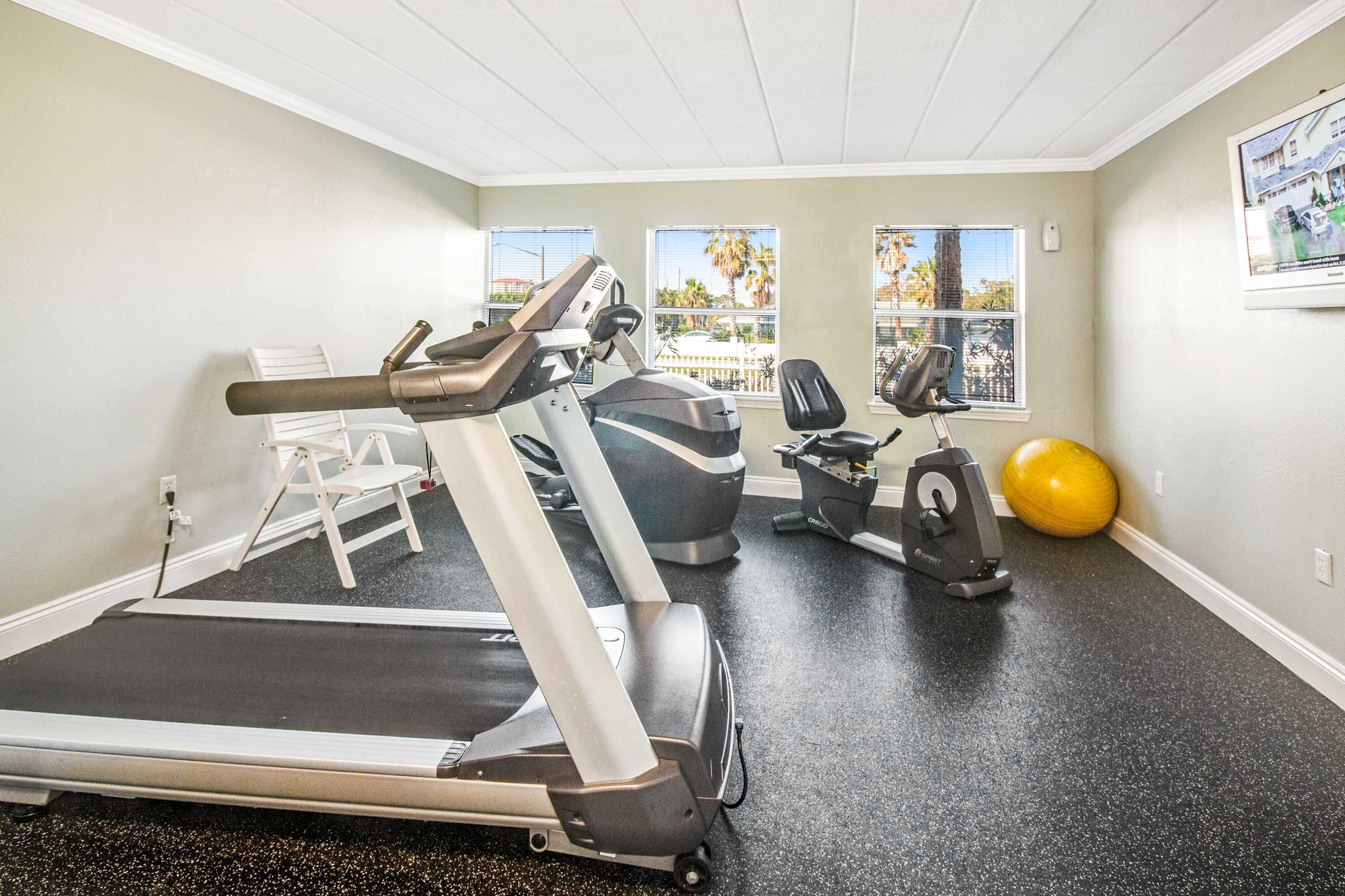 Ein Heimfitnessraum mit Laufband, Ergometer und Übungsball.