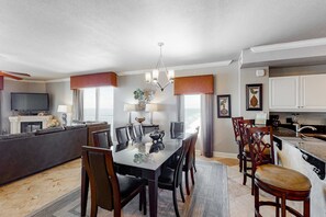 A modern kitchen with a dining area, a fireplace, and a flat-screen TV. - Gulf-front corner condo w/ amazing view, large balcony, pools & hot tubs (Panama City Beach)