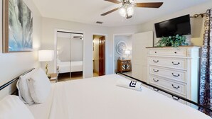 A hotel room with a bed, a ceiling fan, a TV, a dresser, and a plant. - Condo close to the beach with pools, dock & tennis - snowbird-friendly (Panama City Beach)