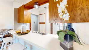 A modern kitchen with a white countertop, wooden ceiling beams, a sink, and a potted orchid. - Condo close to the beach with pools, dock & tennis - snowbird-friendly (Panama City Beach)