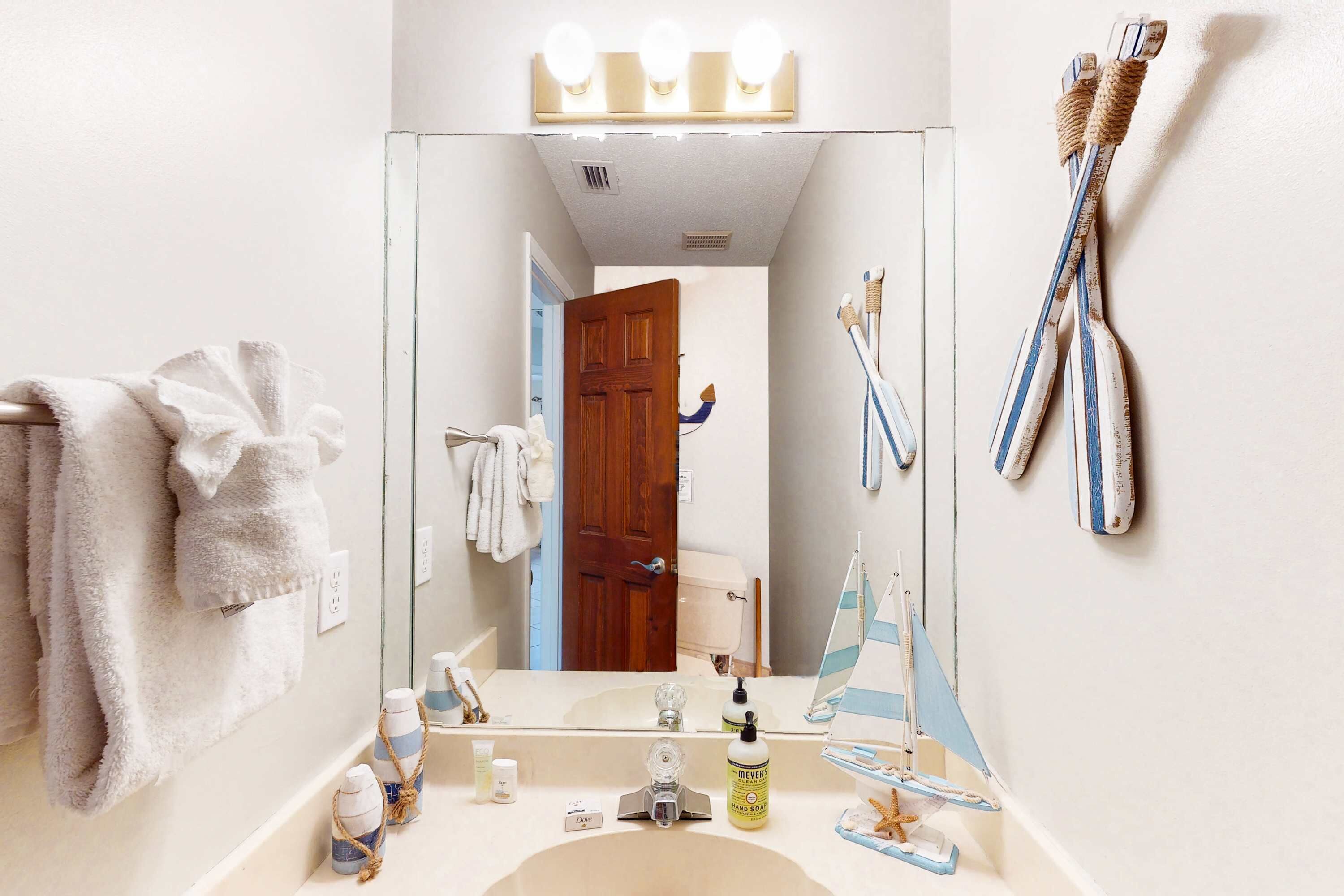 Ein Badezimmer mit einem großen Spiegel, einem Waschbecken und einem Handtuchhalter.
