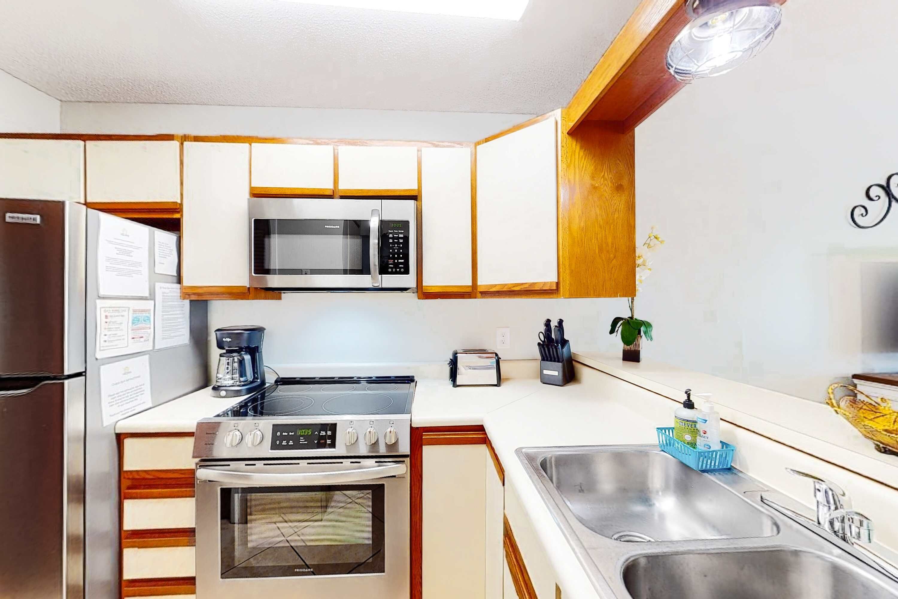 A compact kitchen with a microwave, stove, oven, and a double sink.