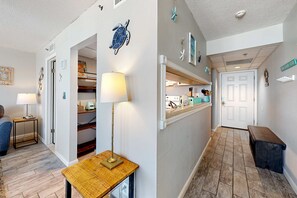 A hallway with a wooden bench, a lamp, and a door leading to a kitchen area. - Gulf-view condo with pools, beach access, gym, grills, & updated interior (Panama City Beach)