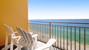 Een balkon met witte stoelen en uitzicht op het strand en de oceaan.