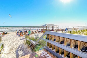 Une plage avec une promenade en bois, des chaises de plage et des parasols.