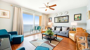 Un salon spacieux avec un balcon, un ventilateur de plafond et une grande fenêtre.