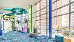 Un espace intérieur vaste et lumineux, avec de grandes fenêtres, un sol à motifs et un mobilier contemporain.