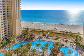 Un resort con zona de piscina, acceso a la playa y un edificio de gran altura.