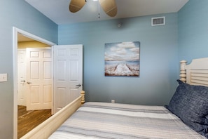 Un dormitorio con cama, un cuadro y una puerta que da a otra habitación.