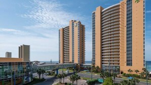 A hotel with multiple high-rise buildings, a glass facade, and a pedestrian bridge. - Fifth-floor oceanfront condo with high-speed WiFi, Gulf view, Pools & Hot tub (Panama City Beach)