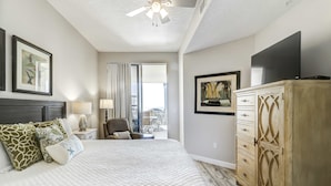 Une chambre à coucher avec un lit, une commode, un téléviseur et une fenêtre avec des rideaux.