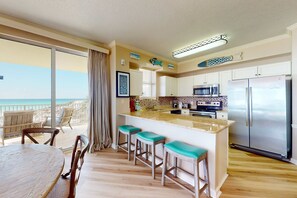 A kitchen with a large island, bar stools, and a view of the beach. - Gulf-front 3-bedroom condo with bonus bunk room & pickleball (Santa Rosa Beach)