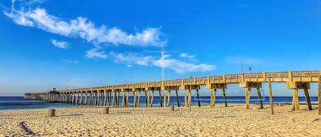 A beach with a wooden pier extending into the ocean.