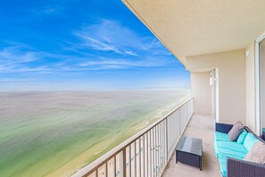 Un balcone con vista sull'oceano, un divano in vimini e un tavolino.