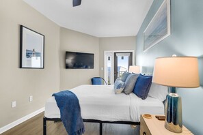 A hotel room with a bed, a TV, a lamp, and a painting on the wall. - 3rd-floor condo with sauna, gym, pool, tennis & pickleball, conference room (Santa Rosa Beach)