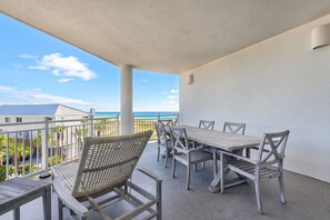 A balcony with a table and chairs, a view of the ocean, and a building in the background. - 3rd-floor condo with sauna, gym, pool, tennis & pickleball, conference room (Santa Rosa Beach)