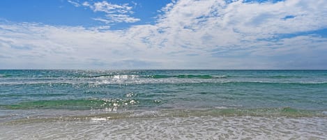 Une plage avec une eau d’un bleu limpide et un rivage sablonneux.