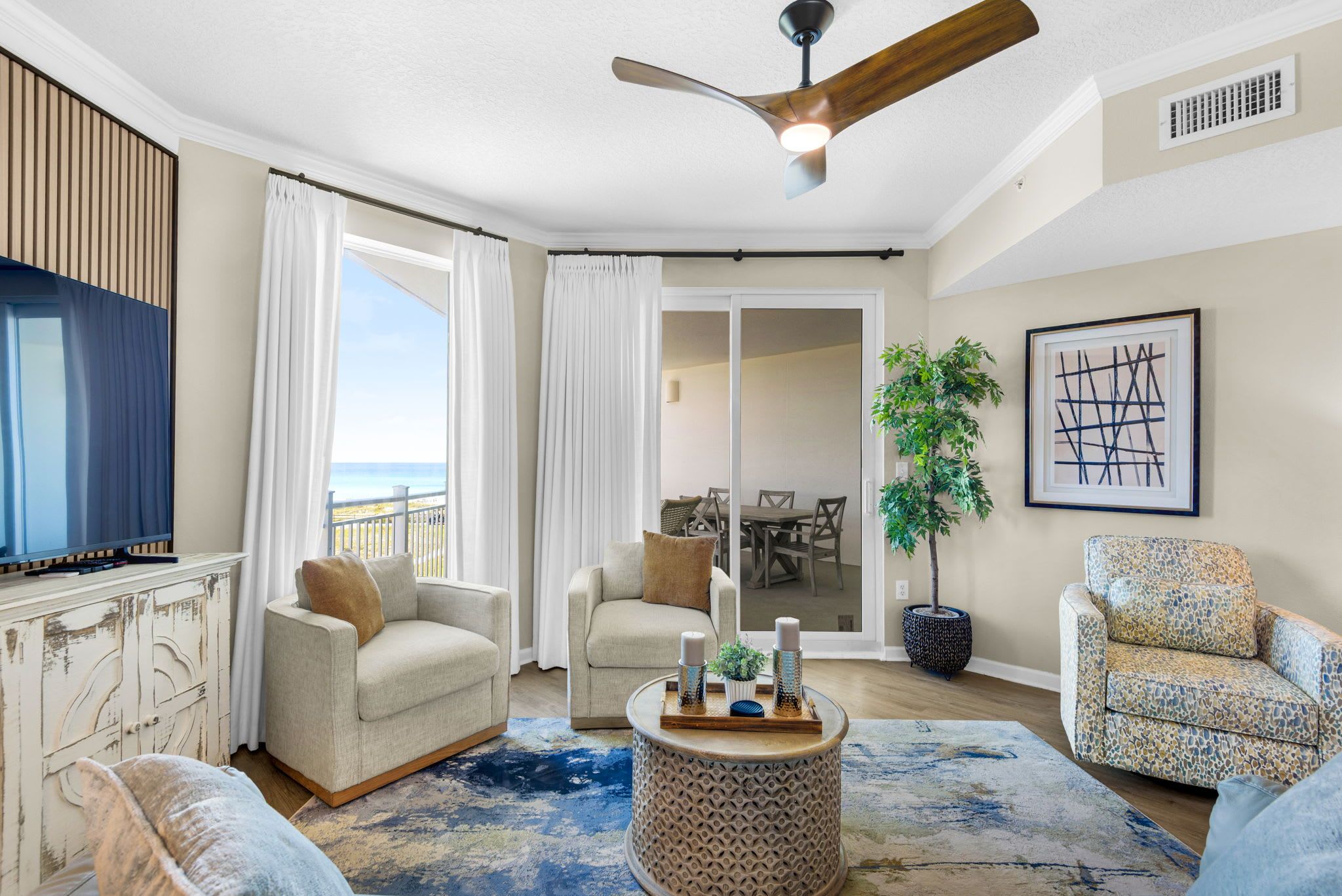 A living room with a TV, two sofas, a coffee table, and a ceiling fan.
