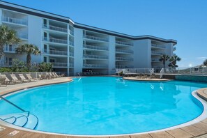 A hotel with a swimming pool, multiple balconies, and palm trees. - 4th-floor condo with beach ambience, lagoon pool, gym, tennis & pickleball (Santa Rosa Beach)
