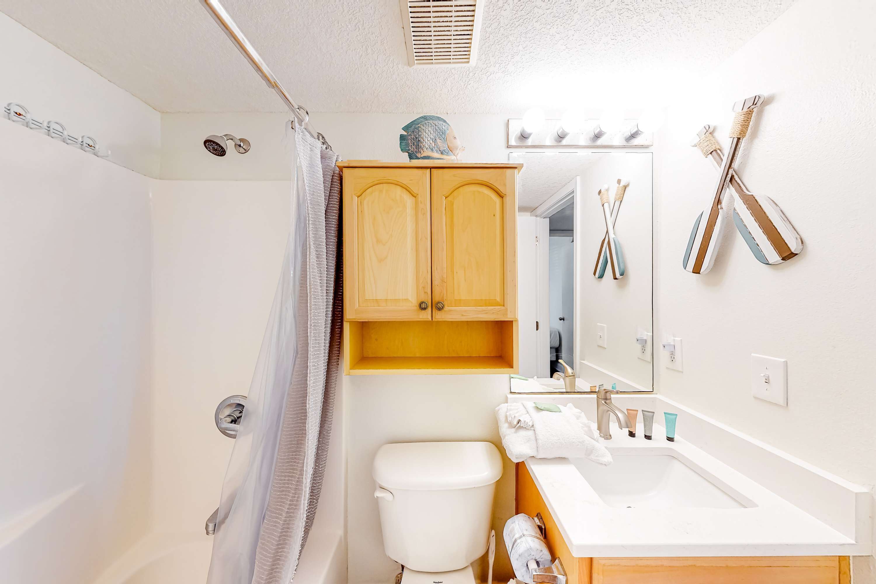 Ein Badezimmer mit Dusche, Toilette, Waschbecken und Holzschränken.