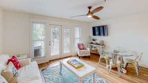 A spacious living room with a sofa, coffee table, and dining area with chairs. - Modern beach condo with pool, hot tub, well-equipped kitchen, balcony, & W&D (Perdido Key)